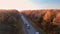 A convoy of several trucks drives along the highway illuminated by the setting sun. The truck is loaded with new cars