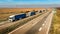 Convoy of White and Blue transportation trucks in line on a countryside highway