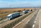 Convoy of White transportation trucks in line on a country highway