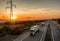 Convoy of White transportation trucks in line on a country highway at sunset