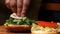 Cook adding lettuce on burger. Stock footage. Preparing burger. Cook hands preparing and making hamburger