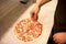 Cook adding onion to salami pizza at pizzeria