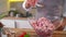 The cook adding the spices in a bowl with the meat, onion and bacon