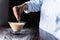 Cook adding sugar to a cream inside a glass cup