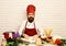 Cook with attentive face in burgundy uniform sits by table