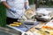 Cook in blue gloves on the street puts hummus to prepare falafel in a metal box