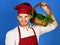 Cook with cheerful face holds wicker basket of fresh veggies.