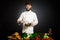 Cook chef with vegetables splah and black dark background. Food musical harmony. Chef juggling with vegetables and other food in t