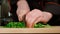Cook cuts a parsley on a cutting board in a kitchen