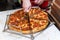 Cook cutting pepperoni pizza in slices