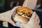 The cook gives a delicious packaged burger to the buyer. street food. close-up