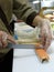 A cook in gloves slices a salmon roll in the kitchen. Japanese kitchen