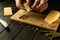 The cook grates hard Dutch cheese on a kitchen board with a grater before preparing a delicious lunch. Cheese dish preparation