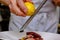 The cook grates the lemon zest to prepare the dish