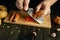 A cook grates raw pork with a grater to prepare a vegetable dish. Vegetable diet cooking concept on kitchen table