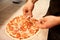 Cook hands adding ham to salami pizza at pizzeria