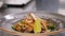 Cook hands placing a piece of lime on avocado salad with grilled meat