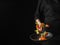 The cook holds in his hand a frying pan with pieces of red fish and vegetables. Levitation. Black background. There is an empty
