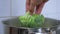 A cook or housewife puts fresh broccoli in a pot of boiling water.
