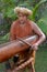 Cook Islander man plays music on a large wooden log Pate drum in