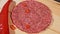 Cook makes meat medallions for burgers. Pouring spices pepper and salt. Meat marbled beef lies on food wooden board for