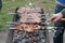 Cook meat on skewers. Man hand turns grilled meat on mangal. Cooking picnic food.