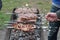 Cook meat on skewers. Man hand turns grilled meat on mangal. Cooking picnic food.