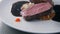 The cook pours sauce on plate with roast beef steak