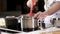 Cook prepares food in restauran kitchen. mixes sauce in  saucepan on the stove.