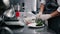 Cook puts lettuce on a white flat dish.