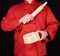 Cook in a red uniform holding a wooden rolling pin and round sieve