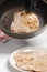 The cook removes the fried flatbread from the pan