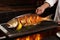 cook removing a whole grilled fish for serving