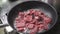 Cook roasts meat pieces in frying pan on electric stove