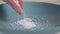 Cook`s hand sprinkles coarse salt on a blue plate