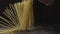 Cook\'s hand throws raw uncooked Italian pasta on a wooden rustic table on a black background. Slow motion, Full HD video