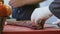 Cook`s hands cutting into a large piece of raw meat using a butcher`s knife