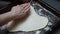 The cook's hands modeling dough in a heart shape on the baking tray. Preparing heart shaped pizza for Valentine's Day