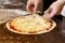 Cook`s hands putting cheese on tomato base pizza.