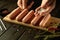 A cook salts raw meat sausages before grilling. Concept of cooking fried Munich sausages on kitchen table with spices