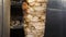 Cook slices chicken shawarma on a skewer to make doner kebab