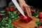 cook slicing paprika on a wooden chopping board.