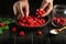 The cook sorts fresh raspberries before making sweet jam in the kitchen. Close-up of a chef hands while working. Copy space