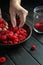 The cook sorts fresh raspberries before preparing a cold drink in the kitchen. Close-up of chef hands while working. Copy space