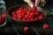 The cook sorts through fresh ripe raspberries before preparing a sweet compote in a jar. Close-up of chef hands while working