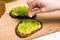 The cook sprinkles spices on a ready-made avocado sandwich. Healthy food for Breakfast, lunch or dinner. Vegetarian recipe