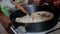 Cook straightens wooden spatulas fish which is fried in a pan.