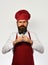 Cook with strict face in burgundy uniform shows cutlery.