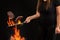 Cook with tattooed hands, dressed in leggings and t-shirt. Holding wok pan above fire and frying two beef steaks against