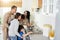 Cook together. Hispanic parents looking happy while standing in the kitchen with children and cooking dinner together at